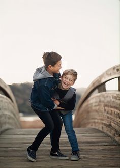 two young children are hugging on a bridge