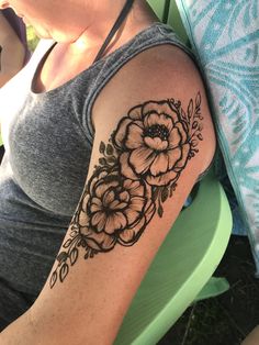 a woman's arm with black and white flowers on the left side of her arm