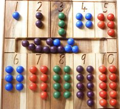 a wooden board game with colorful balls and numbers on the boards, all in different colors