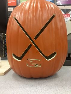 a carved pumpkin with hockey sticks on it's face sitting on a counter in a store