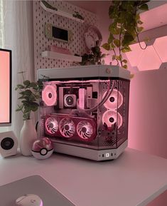 a computer with pink lights on it sitting on top of a desk next to a plant