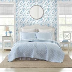 a bedroom with blue and white wallpaper and bedding in it's center