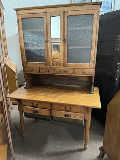 an old wooden desk with glass doors and drawers