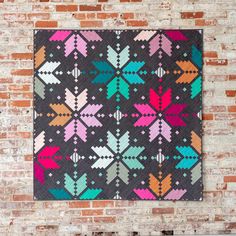 a colorful quilt hanging on a brick wall