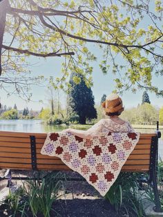 a person sitting on a bench with a crocheted blanket