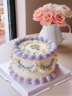 a three tiered cake sitting on top of a table next to a vase filled with flowers