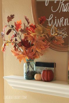 a vase filled with autumn leaves on top of a fireplace mantel next to a sign that says thank giving