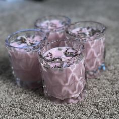 four glasses filled with pink liquid on top of a carpet