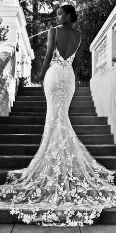 a woman standing on some steps wearing a dress with floral appliques and an open back