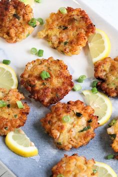 crab cakes with lemon wedges and scallions on a plate