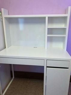 a white desk with shelves and drawers in a purple walled room next to a wall