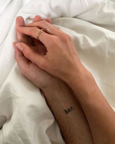 a person laying in bed with their hand on the other side of his arm, holding onto each other's fingers