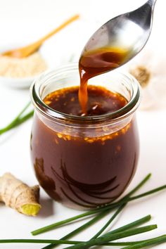 a spoon is pouring sauce into a jar