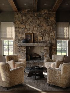 a living room with two chairs and a fire place in front of a stone fireplace