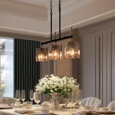 a chandelier hanging over a dining room table with plates and glasses on it