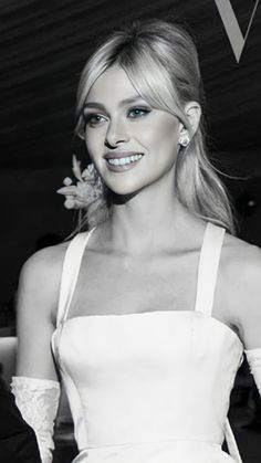 a black and white photo of a woman in a dress with flowers on her shoulder