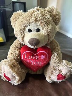 a brown teddy bear holding a red heart with the words love you on it's chest