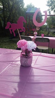 a pink table topped with a vase filled with white and pink flowers next to a sign that says go