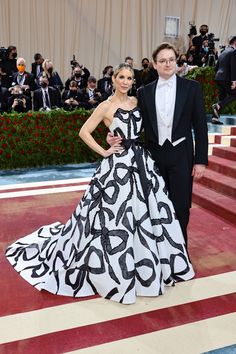 a man in a tuxedo standing next to a woman in a black and white dress