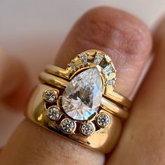 a close up of a person's hand holding a ring with a diamond on it