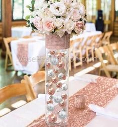 a tall vase filled with flowers and pearls on top of a table covered in pink sequins