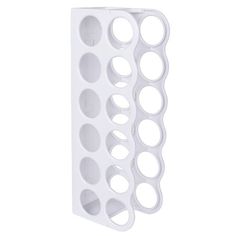 a white wall mounted bottle holder with circles on it's sides and holes in the bottom