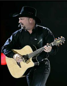 a man with a cowboy hat playing an acoustic guitar