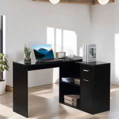 a black desk with a laptop on top of it in front of a potted plant