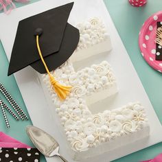 a graduation cake with white frosting and flowers on it, next to a spoon