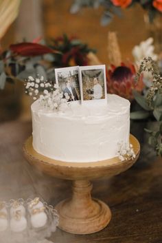 a wedding cake with two photos on top and flowers in the backgroung