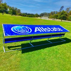 an allstate sign in the middle of a grassy field with trees in the background