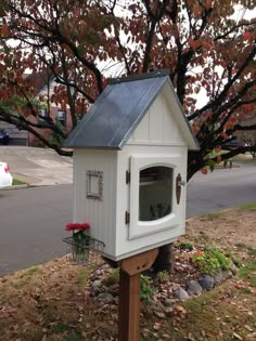 a small white bird house sitting in the grass