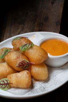 some food on a white plate with dipping sauce