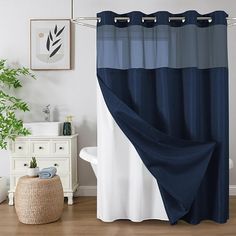 a bathroom with a blue shower curtain and white bathtub in the corner, next to a potted plant