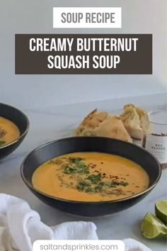 two bowls of creamy butternut squash soup with limes and pita bread on the side