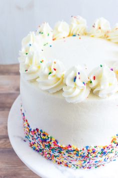 a cake with white frosting and sprinkles on a wooden table top