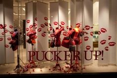 a display window with red lipstick and fake lips on it's glass walls that says pucker up