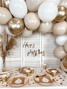 a table topped with lots of white and gold balloons