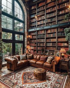 a living room with lots of bookshelves and couches in front of a large window