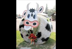 a fake cow head sitting in the grass next to a flower pot with flowers on it