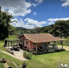 a small pink house with a hammock in the yard next to some trees