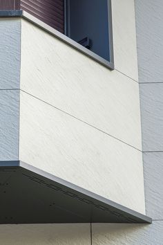 a bird is perched on the ledge of a building's window sill as it looks out