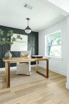 a room with wood flooring and black wallpaper on the walls, along with a wooden dining table surrounded by two white chairs