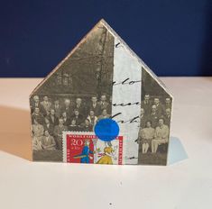 a small house made out of paper with pictures on the front and sides, sitting on a table