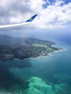 an airplane wing flying over the ocean and land