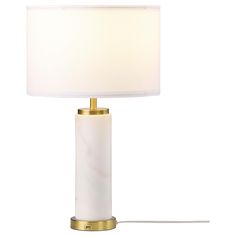 a white lamp with a gold base and a light shade on the top, sitting against a white background