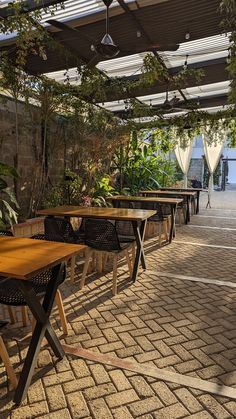 tables and chairs are lined up under an awning with plants growing on the roof