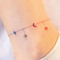 a small tattoo on the ankle of a woman with an airplane and planets attached to it