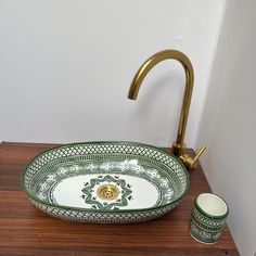 a green and white bowl sink sitting on top of a wooden counter next to a faucet