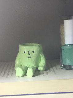 a green toy sitting on top of a book next to a bottle